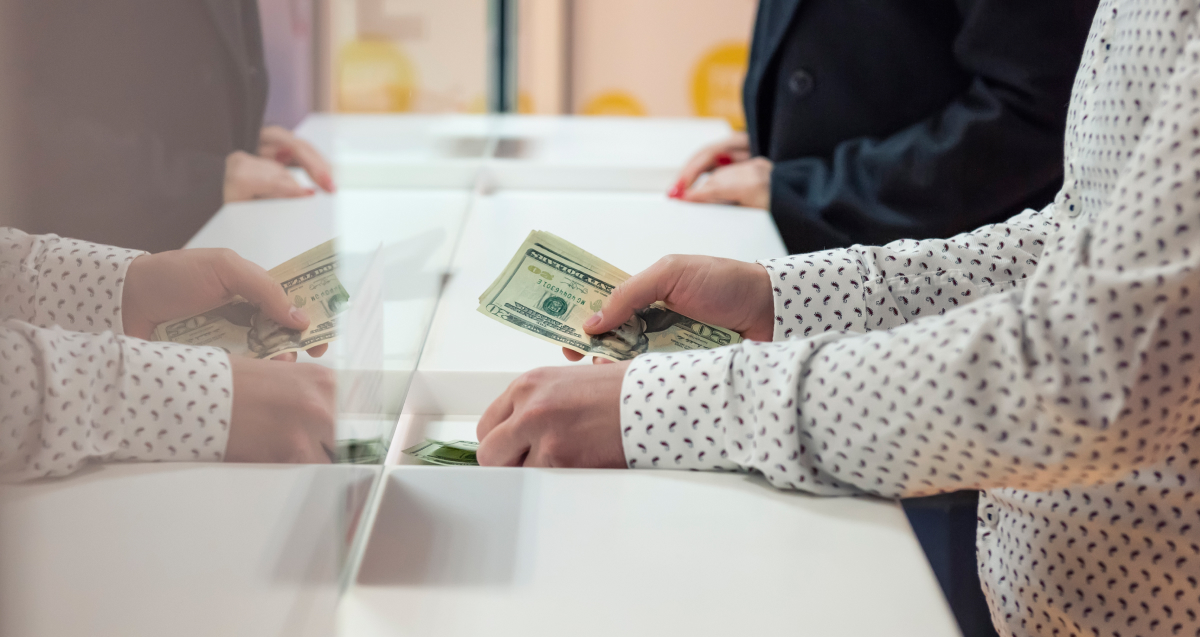 Person exchanging money with bank teller